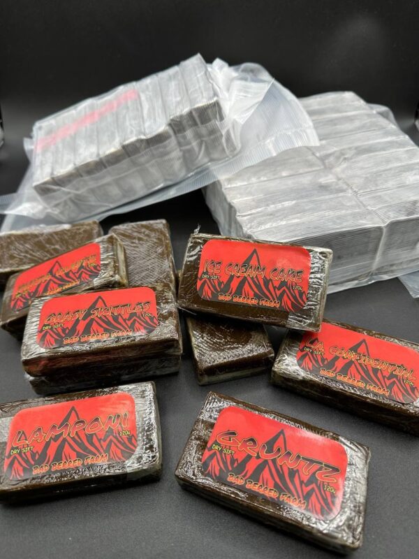 Premium Dry Sift 120U hash by Bad Berred Farm, golden trichomes with a fine, clean texture in branded glass packaging